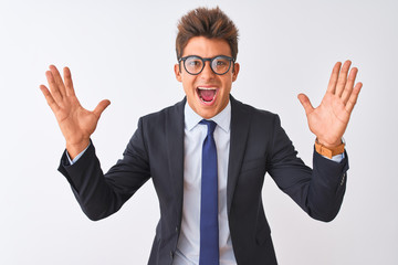 Young handsome businessman wearing suit and glasses over isolated white background celebrating crazy and amazed for success with arms raised and open eyes screaming excited. Winner concept