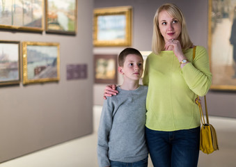 Mother and son looking at paintings in halls of museum