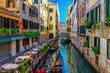 Narrow canal with gondola and tables of restaurant in Venice, Italy. Architecture and landmark of Venice. Cozy cityscape of Venice.