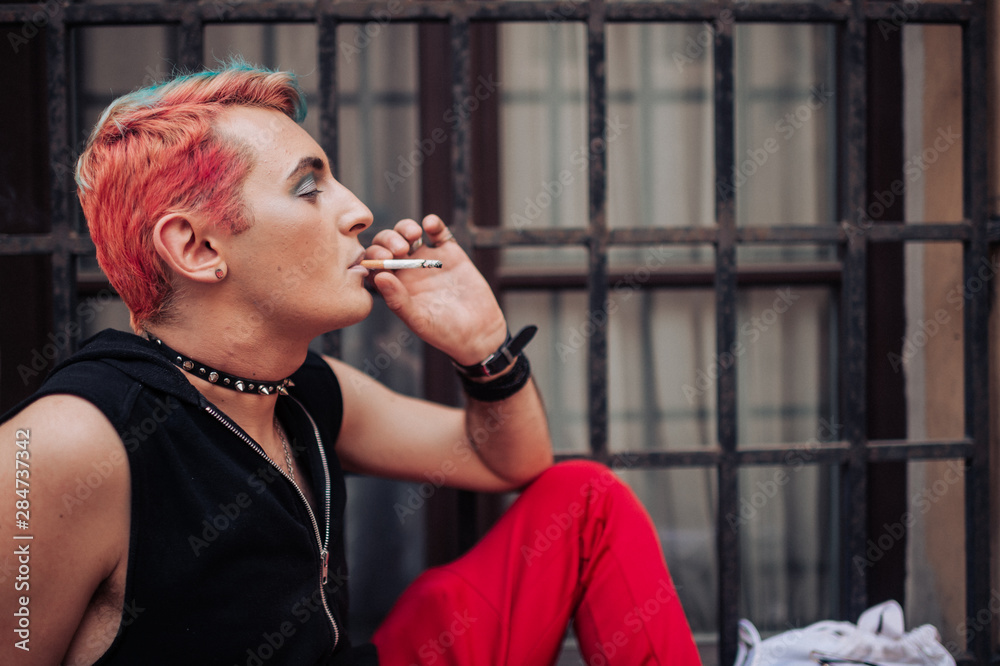 Lifestyle portrait of gay man smoking cigarette with satisfied facial  expression. Stock Photo