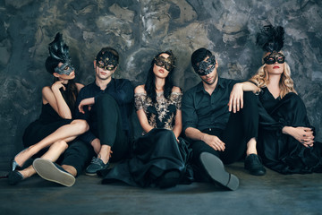 Canvas Print - Group of friends in masquerade carnival mask sitting on floor relax after party