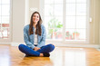 © Krakenimages.com - Beautiful young woman sitting on the floor at home with a happy and cool smile on face. Lucky person.