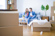 © Krakenimages.com - Young couple relaxing drinking a cup of coffee sitting at sofa of  new home with cardboard boxes around them, very happy moving to a new apartment