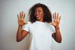 © Krakenimages.com - Young african american woman wearing t-shirt standing over isolated white background showing and pointing up with fingers number ten while smiling confident and happy.