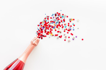 Champagne bottle with colorful party streamers for celebration on white background top view mock up