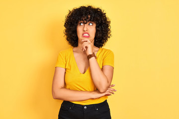 Sticker - Young arab woman with curly hair wearing t-shirt standing over isolated yellow background Thinking worried about a question, concerned and nervous with hand on chin