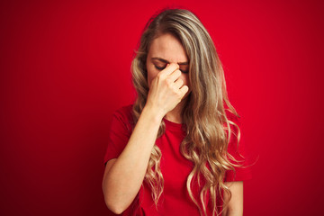 Sticker - Young beautiful woman wearing basic t-shirt standing over red isolated background tired rubbing nose and eyes feeling fatigue and headache. Stress and frustration concept.