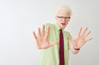 © Krakenimages.com - Young albino businessman wearing shirt and tie standing over isolated white background afraid and terrified with fear expression stop gesture with hands, shouting in shock. Panic concept.