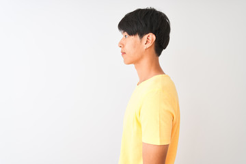 Wall Mural - Chinese man wearing yellow casual t-shirt standing over isolated white background looking to side, relax profile pose with natural face with confident smile.