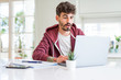 © Krakenimages.com - Young student man using computer laptop and notebook scared in shock with a surprise face, afraid and excited with fear expression