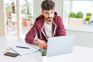 Sticker - Young student man using computer laptop and notebook with a confident expression on smart face thinking serious