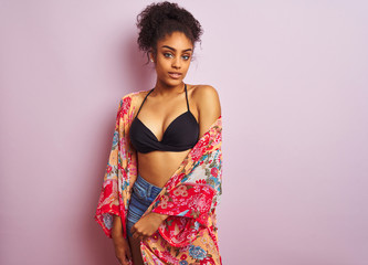 Young beautiful african american woman on vacation standing wearing bikini and colorful caftan