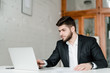 © Anastasia - handsome businessman in a suit uses laptop in the office