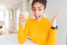 Young African American Woman Drinking A Glass Of Fresh Orange Juice Very Happy And Excited, Winner Expression Celebrating Victory Screaming With Big Smile And Raised Hands