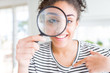 © Krakenimages.com - Young african american woman looking through magnifying glass with surprise face pointing finger to himself