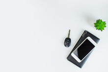 Picture Of A Smartphone, Placed On A Black Leather Bag With Car Keys And Plant Pots On A White Background