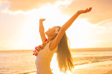 Wall Mural - Hawaii hula dancer woman wearing flower necklace lei on sunset beach dancing with open arms free in sunset relaxing on hawaiian travel vacation. Asian girl with fresh flowers hair, traditional dance.