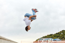 Young Man Throwing A Somersault Outdoors, Full Length Side View Photo, Copy Space