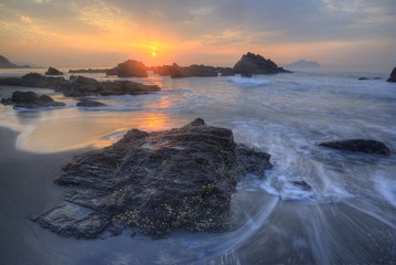 Wall Mural - Golden rays of rising sun light up the sea waves at a beautiful rocky beach on Yilan Coast near Taipei, Taiwan ~ Fascinating sunrise scenery at Ilan seashore under dramatic dawning sky (Long Exposure)