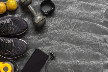 Wall Mural - Fit and Healthy lifestyle background concept. sport shoes, smart mobile phone, dumbbell, smart watch, bottle of water, kiwi fruit on grunge black chalk board. Top view flat lay style.