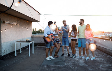 Group of happy friends having party on rooftop