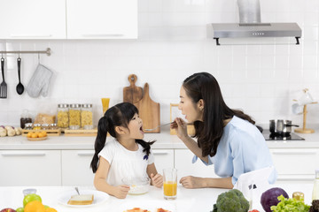 Happy Asian family Mother and Little girl are eating breakfast, cereal  with milk in the kitchen at home. Healthy food concept For the strength of the body