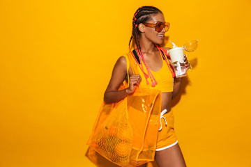 Canvas Print - Image of happy african american woman wearing sunglasses carrying bag and holding plastic cup