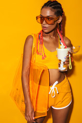 Canvas Print - Image of seductive african american woman wearing sunglasses carrying bag and holding plastic cup