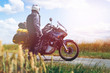 A male driver in a raincoat is standing by adventure motorbike with side bags. a motorcycle tour journey. Outdoor. light warm tinting, glow, freedom concept. rider equipment.