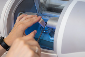 woman sets a workpiece in a dental milling machine for the manufacture of a dental crown