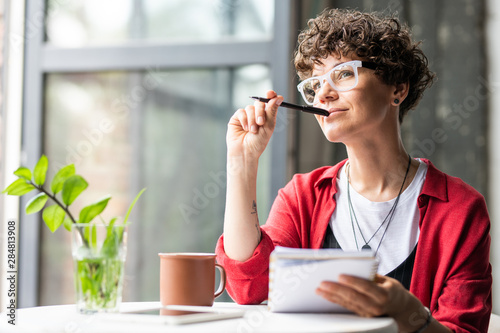 Fotografía Young pensive female in eyeglasses thinking of new creative ideas