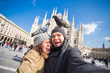 © satura_ - Couple taking self portrait with pigeon in Duomo square in Milan. Winter traveling, Italy and relationship concept