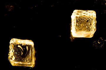 ice cubes and water drop on light golden background.