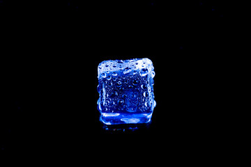 Blue ice cubes on black wet table.