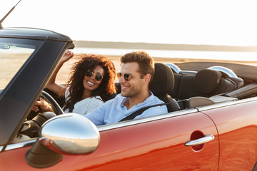 Canvas Print - Beautiful young multiethnic couple riding in a convertible