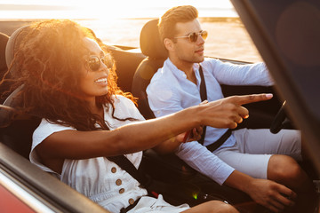 Beautiful young multiethnic couple riding in a convertible