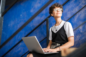 Canvas Print - Happy young modern student or manager in casualwear using laptop