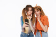 © Drobot Dean - Full length portrait of two excited girls wearing casual clothes having fun and using smartphone together