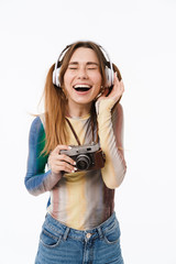 Wall Mural - Portrait of pleased young woman wearing headphones smiling and holding retro camera