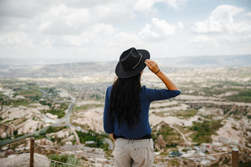 Wall Mural - Girl traveler in a hat on the background of the valley in Cappadocia. Goreme, Turkey