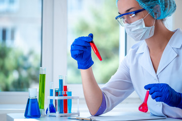 Female laboratory assistant conducts clinical laboratory research, holds test tubes in his hands. Medicine, pharmacy and cosmetology concept. Scientific glassware for test