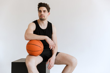 Wall Mural - Concentrated serious strong young sports man basketball player holding ball isolated over white background.