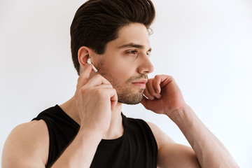 Poster - Handsome concentrated young sports man isolated over white wall background listening music with earphones.