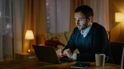 Aufkleber - Respectable Looking Middle Aged Man Works on a Laptop from His House. His Apartment Has View on a Big City. Inside it's Warm and cosy.