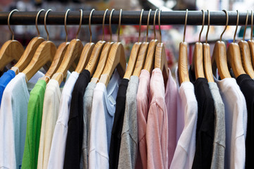 Colorful shirts on wooden hangers in store, side view