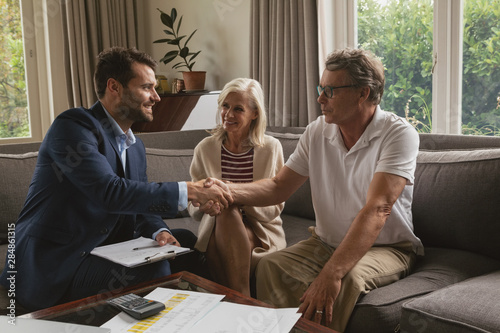 Cuadros en Lienzo Active senior man shaking hands with real estate agent in living room