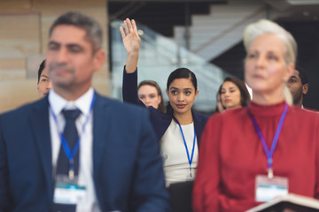 Wall Mural - Young businesswoman raising hand in a business seminar