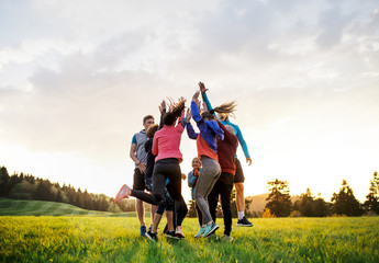 Poster - Large group of fit and active people jumping after doing exercise in nature.