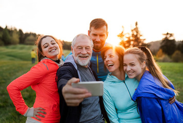 Poster - A group of fit and active people resting after doing exercise in nature, taking selfie.