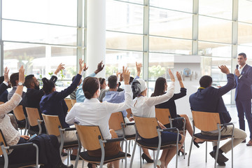 Group of business people raising hands at seminar at conference